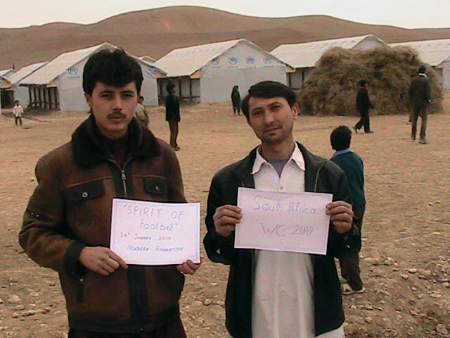 Two Afghan men hold messages of support for The Ball
