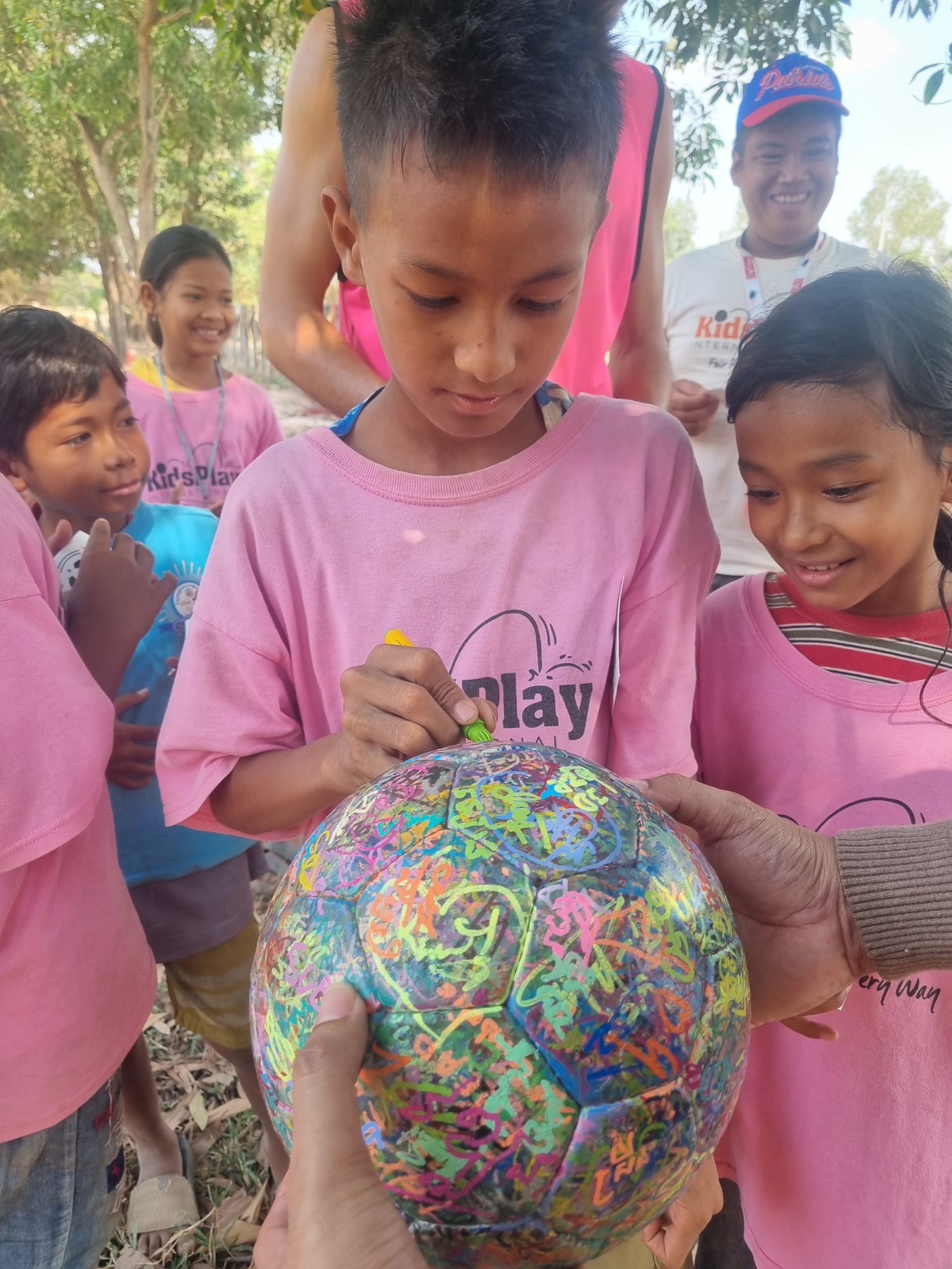 Child signs The Ball at Kids Play International, Cambodia