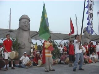 Chinese musicians play in front of a replica of Jeju's ancient statues